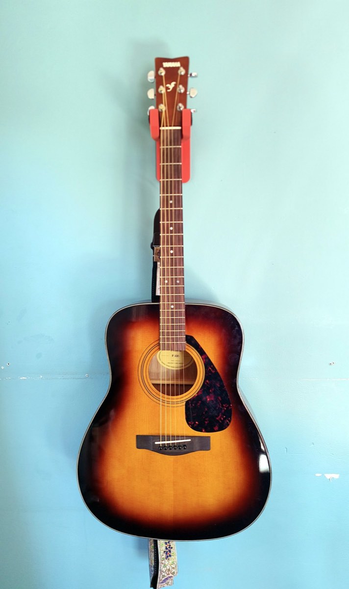 The whole acoustic guitar hanging on the wall from the hook