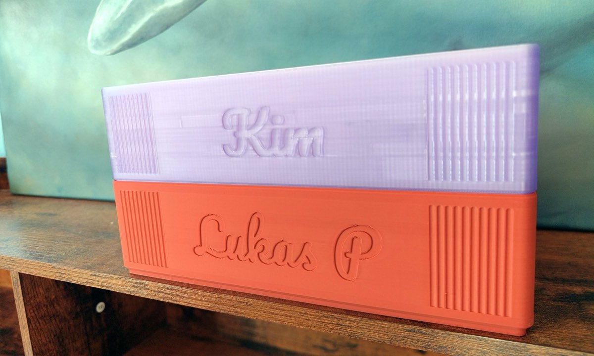 The same two stacked trays seen low from the front, the names cut in cursive